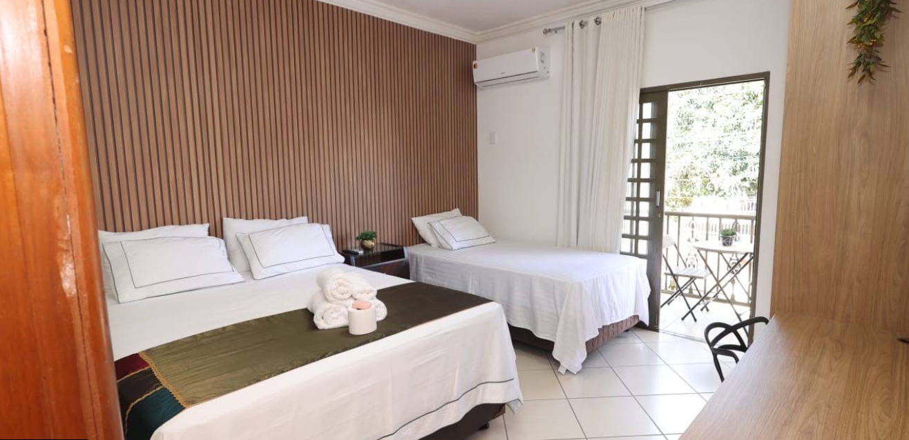 Quarto claro e climatizado da Pousada House Garden com cama de casal, cama de solteiro e varanda